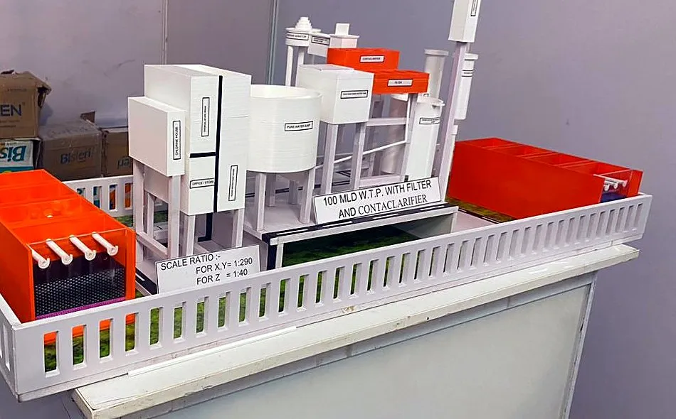 3D-printed water treatment plant model with labelled buildings and a scale-ratio sign reading 1:290 plan, 1:40 height